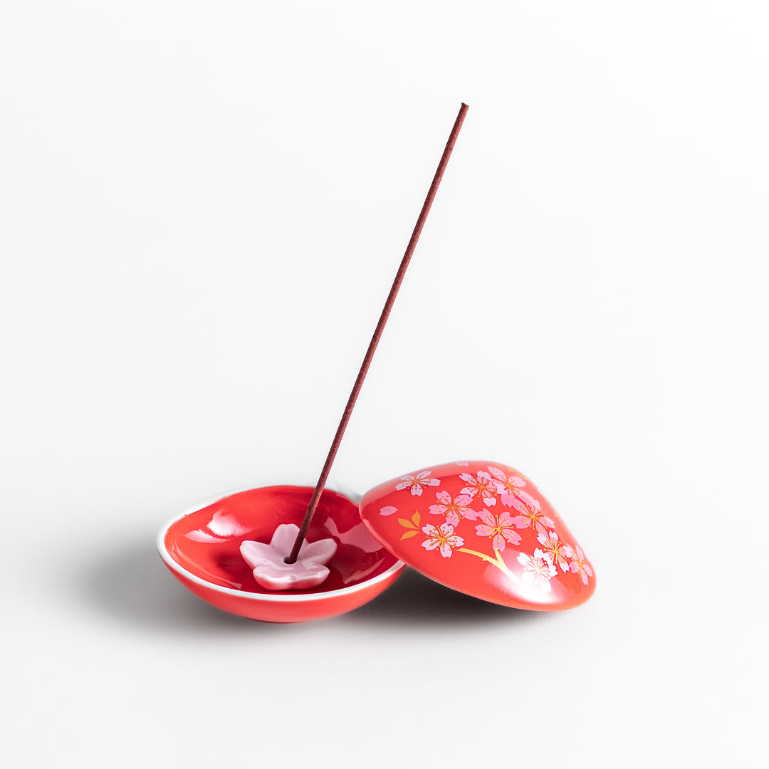 Red sakura shell incense holder with a floral lid and a white cherry blossom-shaped stand, designed to elegantly catch ash while enhancing any space.