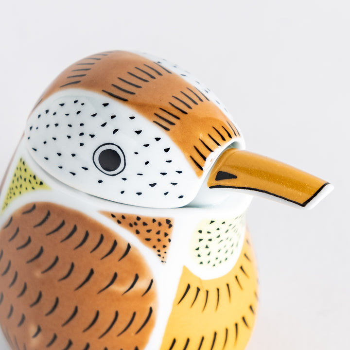 Close-up of the sparrow soy sauce dispenser’s head, highlighting the orange beak and black feather markings.