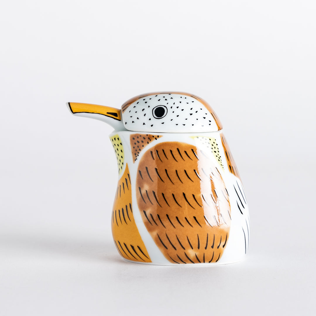 Side profile of the sparrow soy sauce dispenser with an orange beak and intricate feather patterns in brown and yellow.