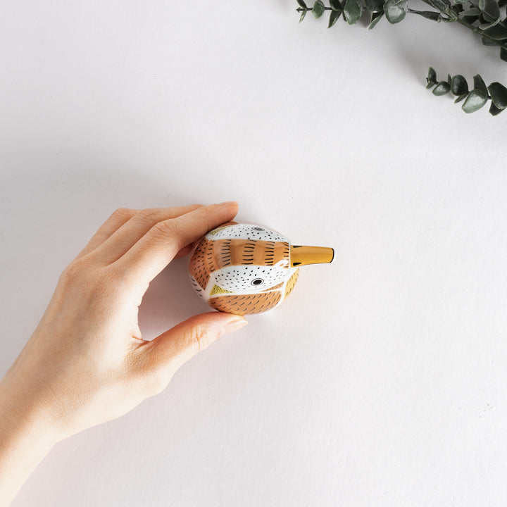 Hand holding the sparrow-shaped soy sauce dispenser, showcasing its compact size and detailed design.