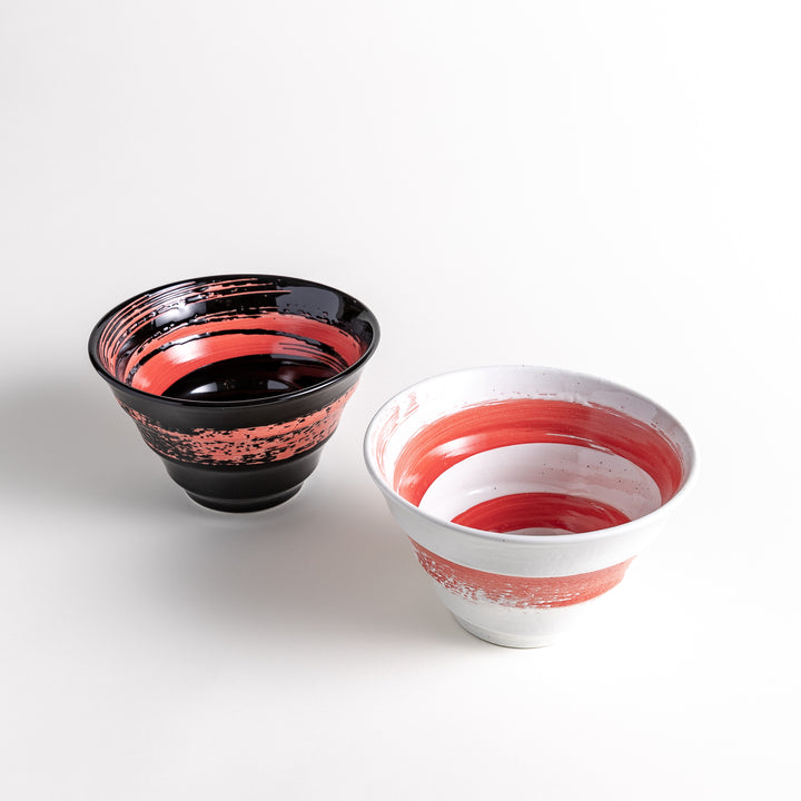 Black and white ramen bowls with red swirl patterns on the inside and outer sides, placed on a white background.