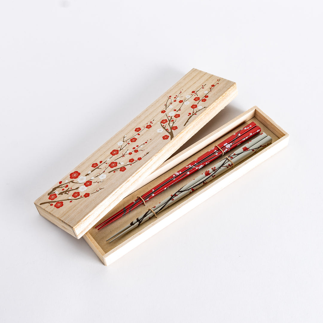 The chopsticks set is placed in a beautiful wooden box, with an intricate plum blossom design on the lid, adding an elegant touch to the presentation.