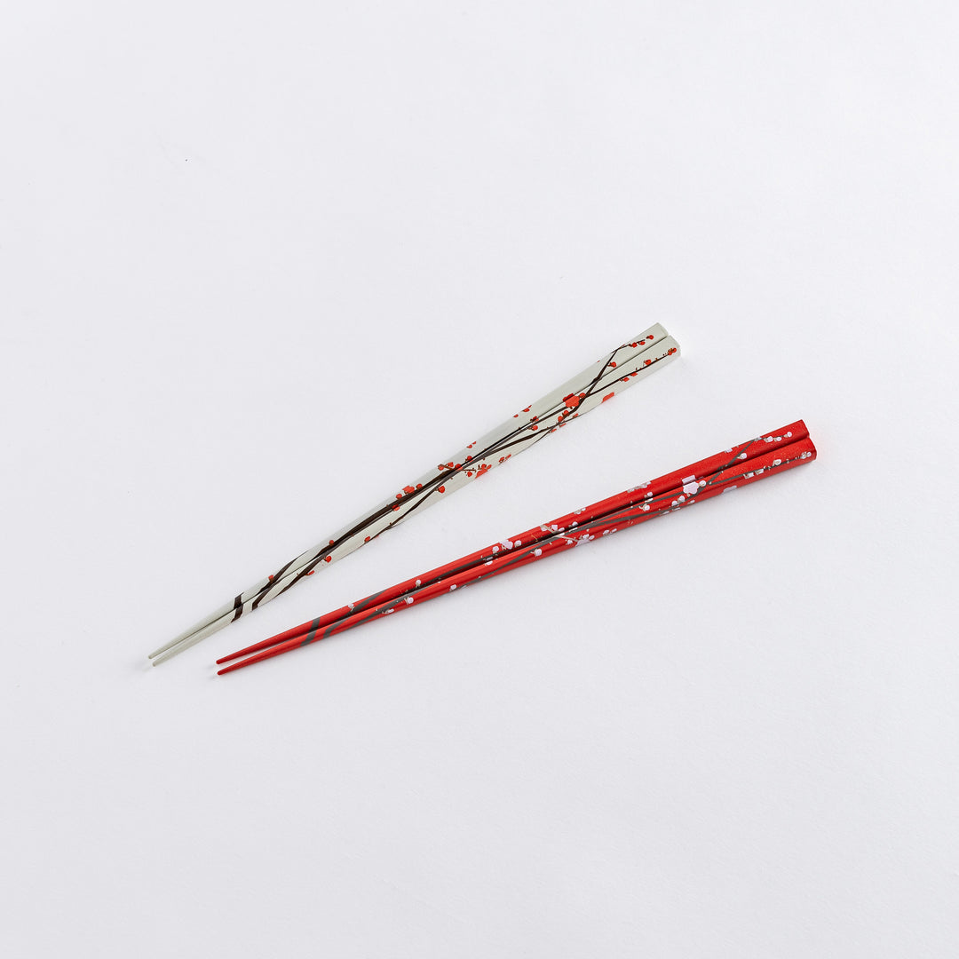 Holding a white chopstick with red plum blossom patterns in hand, showcasing the elegant design.