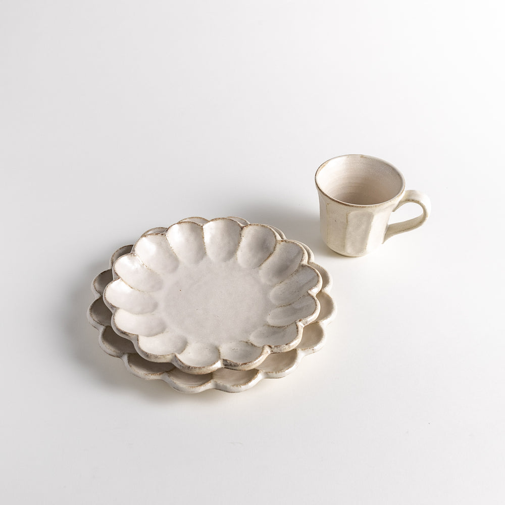 Three-piece Rinka Petal Set stacked with two plates featuring scalloped edges and a cup placed beside them, showcasing a rustic and elegant style.