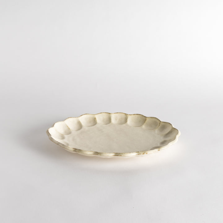 A white ceramic serving plate with a delicate, scalloped oval shape. Available in black or white.