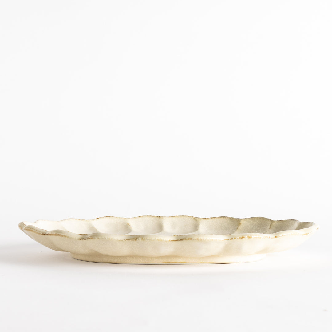 A white ceramic serving plate with a delicate, scalloped oval shape. Available in black or white.