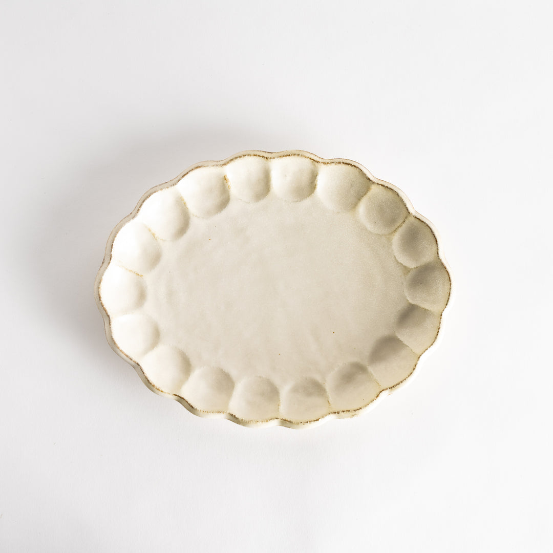 A white ceramic serving plate with a delicate, scalloped oval shape. Available in black or white.