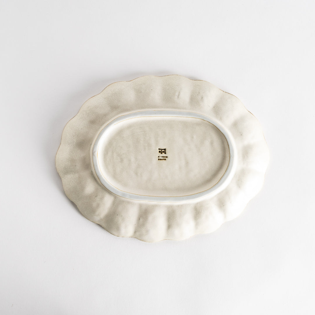 A white ceramic serving plate with a delicate, scalloped oval shape. Available in black or white.