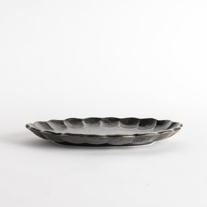 A white ceramic serving plate with a delicate, scalloped oval shape. Available in black or white.