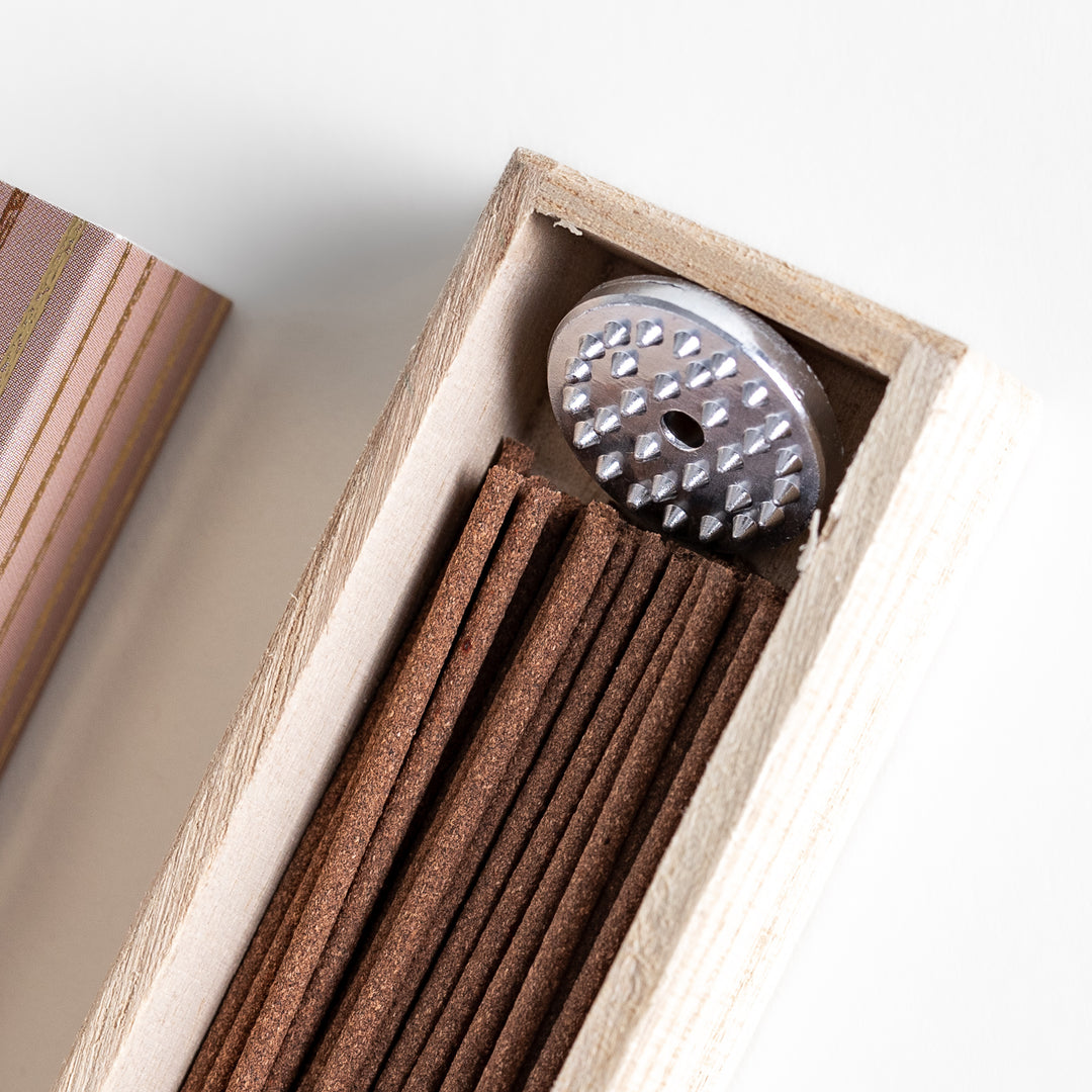 Incense in a light wooden box with rich brown sticks, elegantly packaged in a warm beige design featuring white circular patterns, evoking a soothing coffee aroma.