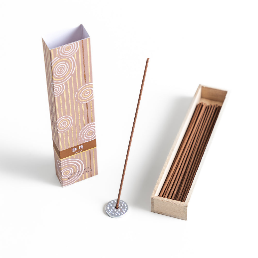 Incense in a light wooden box with rich brown sticks, elegantly packaged in a warm beige design featuring white circular patterns, evoking a soothing coffee aroma.