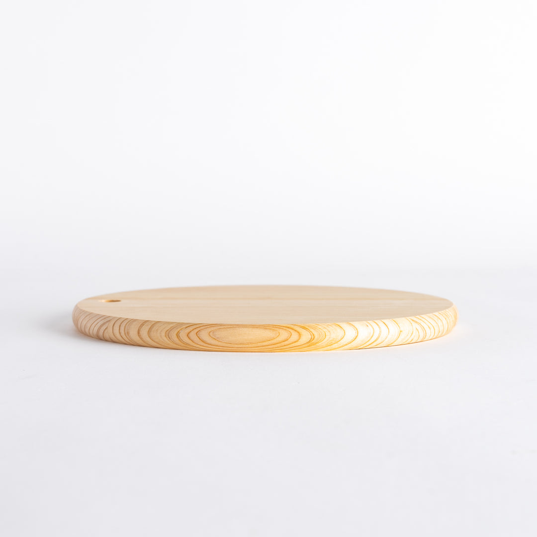 Side view of a round Hinoki cutting board showing its thickness and hole.