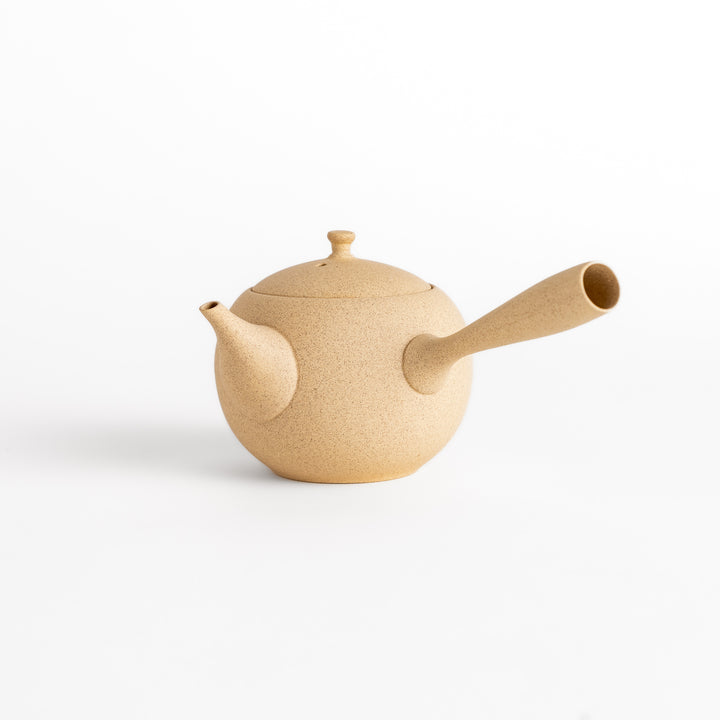 A beige ceramic teapot with a side handle, curved spout, and textured surface, showcasing minimalist Japanese design.