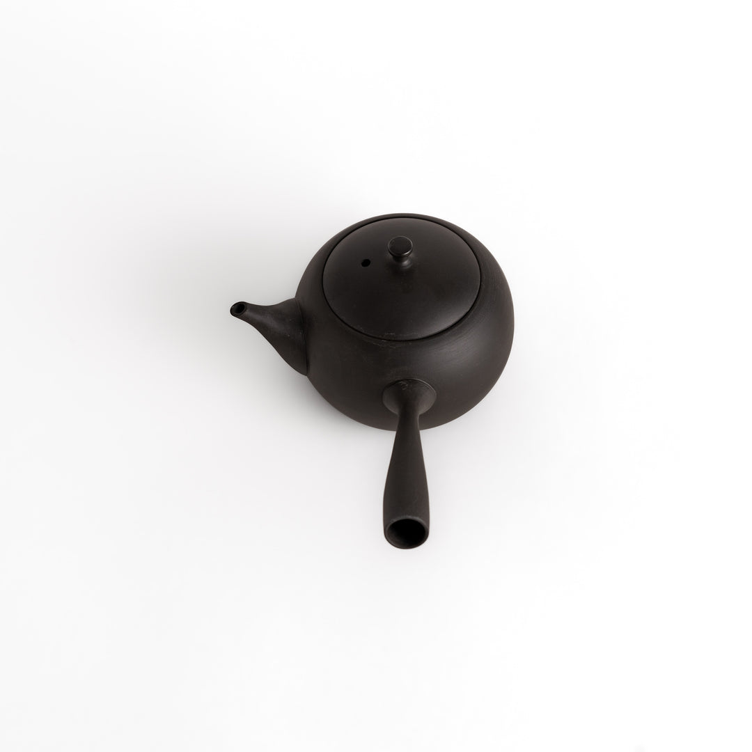 Angled view of the black teapot, emphasizing its smooth matte finish and elegant form.