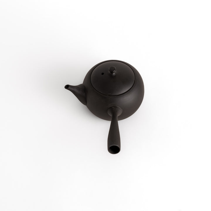 Angled view of the black teapot, emphasizing its smooth matte finish and elegant form.