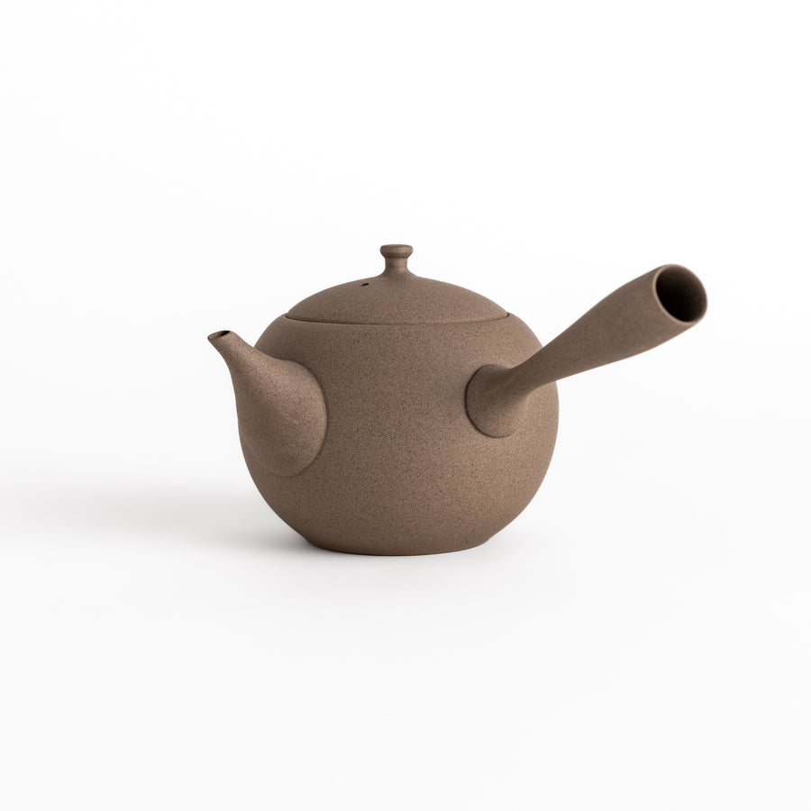 A gray ceramic teapot with a side handle, curved spout, and textured surface, showcasing minimalist Japanese design.