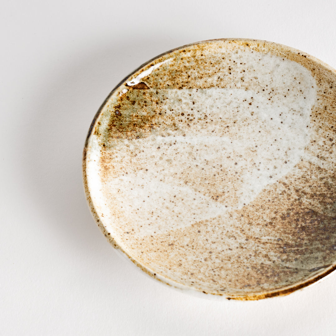 A small dessert plate with a speckled cream and brown glaze, featuring an organic, earthy design.