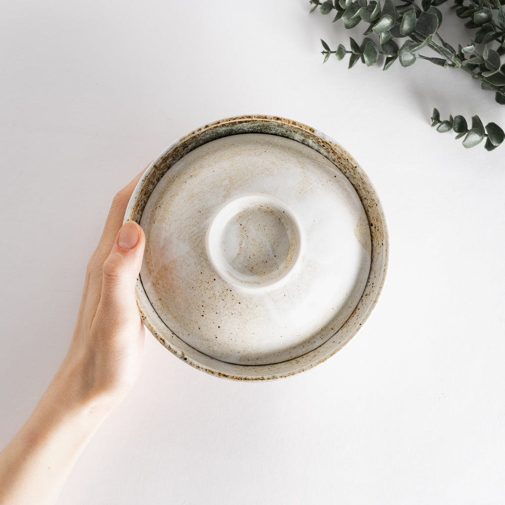 Hand holding a rustic donburi bowl, highlighting its textured finish and organic shape, ideal for warm, comforting meals.