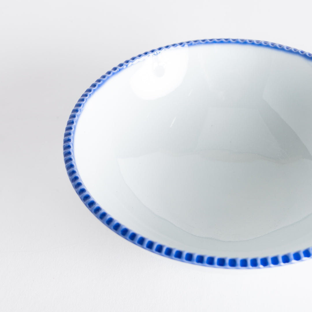 Close-up of the cereal bowl highlighting the blue scalloped edge and smooth white interior.