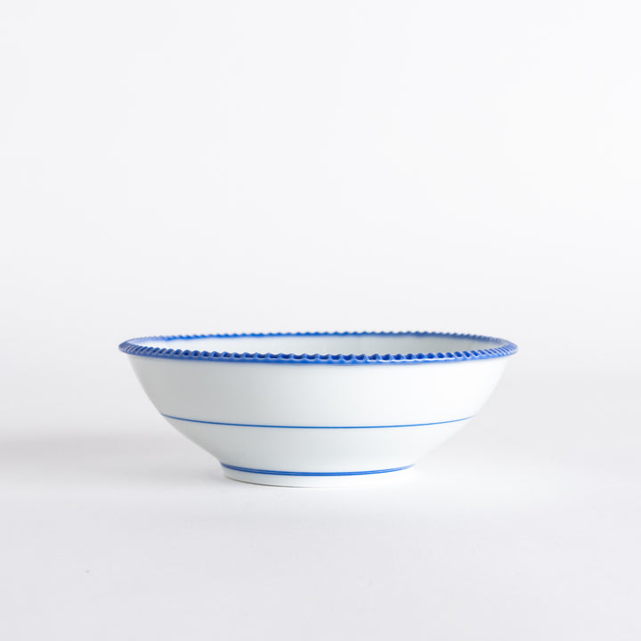 Side view of the cereal bowl displaying its smooth curves and blue scalloped detailing.