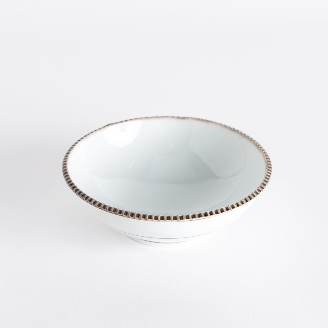 Top view of a cereal bowl with a smooth white interior and a rustic brown scalloped rim.