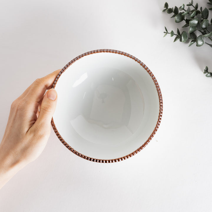 A round white cereal bowl with a rustic scallop-edged border. The border comes in blue, brown, and olive.