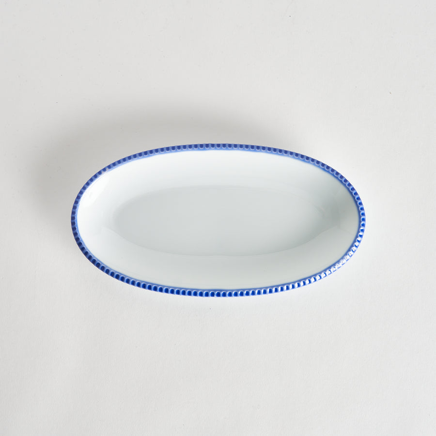 Top-down view of an oval salad platewith rustic scalloped edges and a blue beaded rim, showcasing its simple, elegant design.