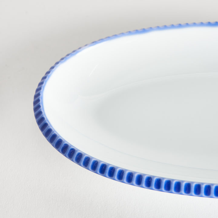 Close-up of the scalloped blue edge on the oval salad plate, highlighting its intricate design.