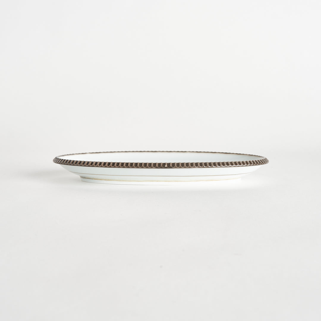 Side view of an oval salad plate with a subtle olive-colored scalloped edge.