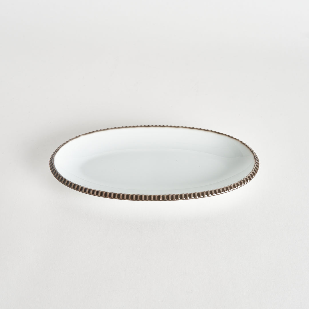 Angled view of an oval salad plate with an olive-colored scalloped edge.