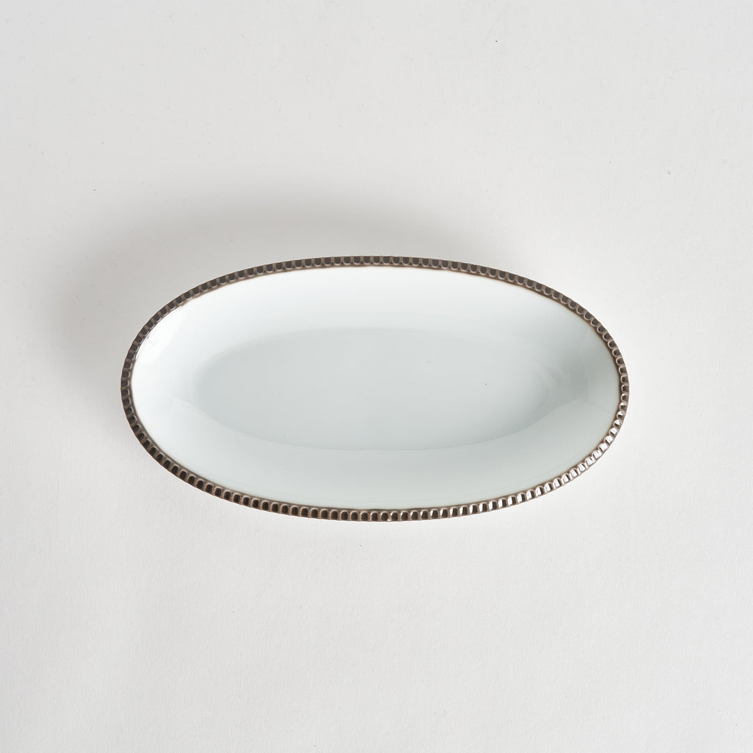 Top-down view of an oval salad platewith rustic scalloped edges and an olive-colored rim, showcasing its simple, elegant design.