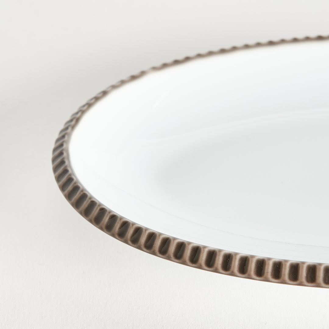 Close-up of the olive-colored scalloped edge of the oval salad plate, highlighting its natural design.