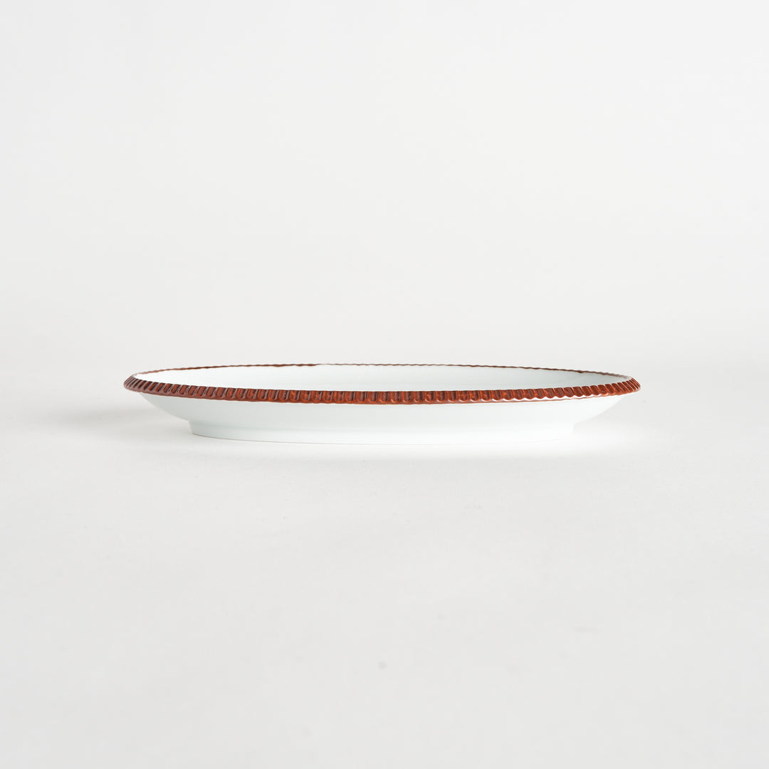 Side view of an oval salad plate featuring a warm brown-colored scalloped edge.