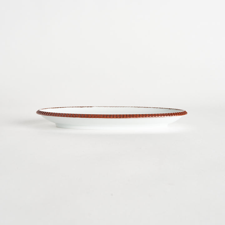 Side view of an oval salad plate featuring a warm brown-colored scalloped edge.