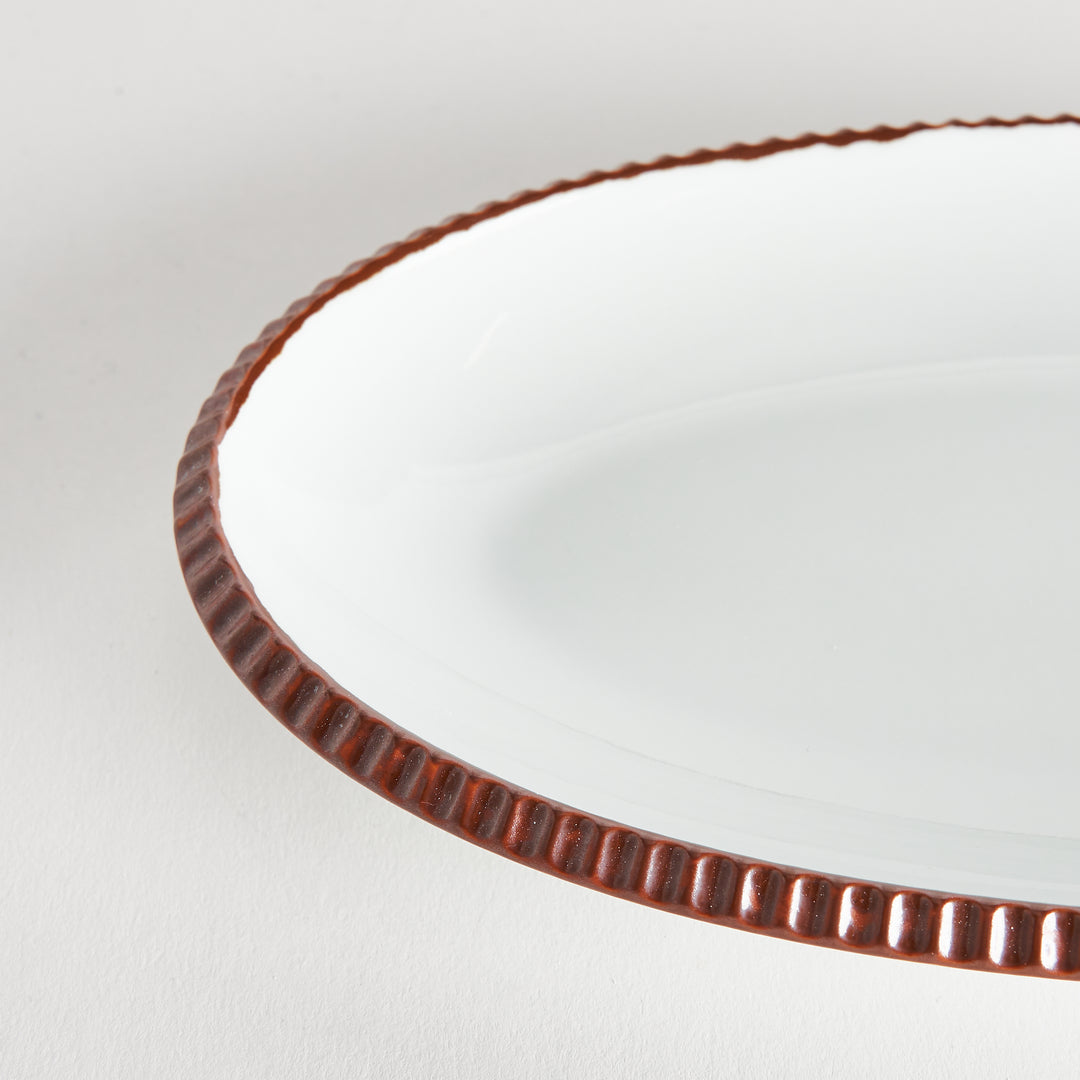 Close-up of the brown-colored scalloped edge of the oval salad plate, emphasizing its detailed design.