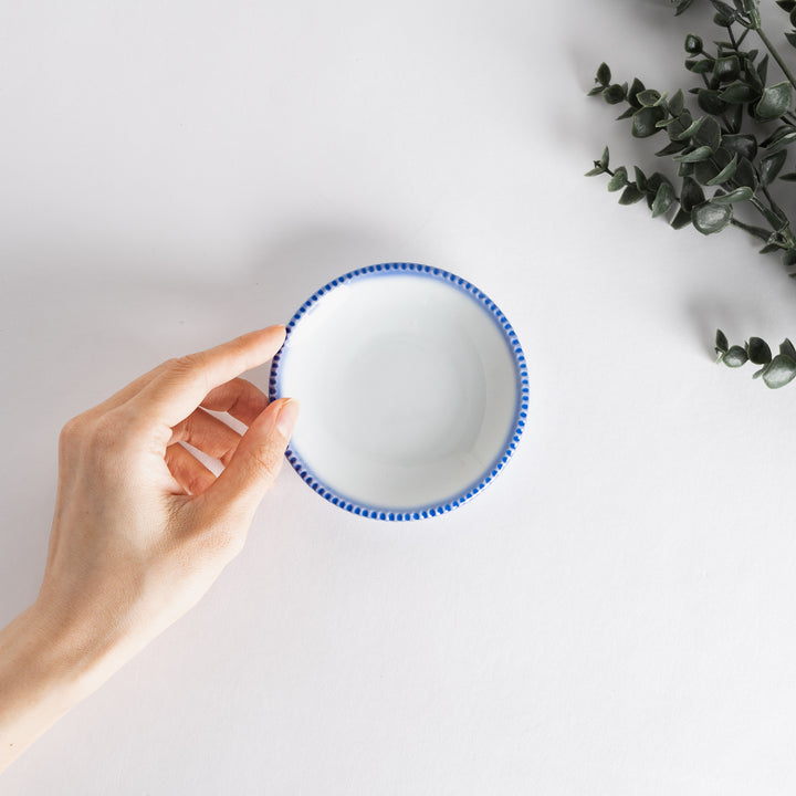 A round white sauce dish with a rustic scallop-edged border. The border comes in blue, brown, and olive.