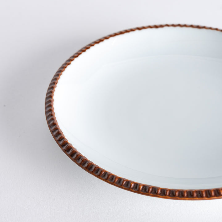 A round white dessert plate with a rustic scallop-edged border. The border comes in blue, brown, and olive.