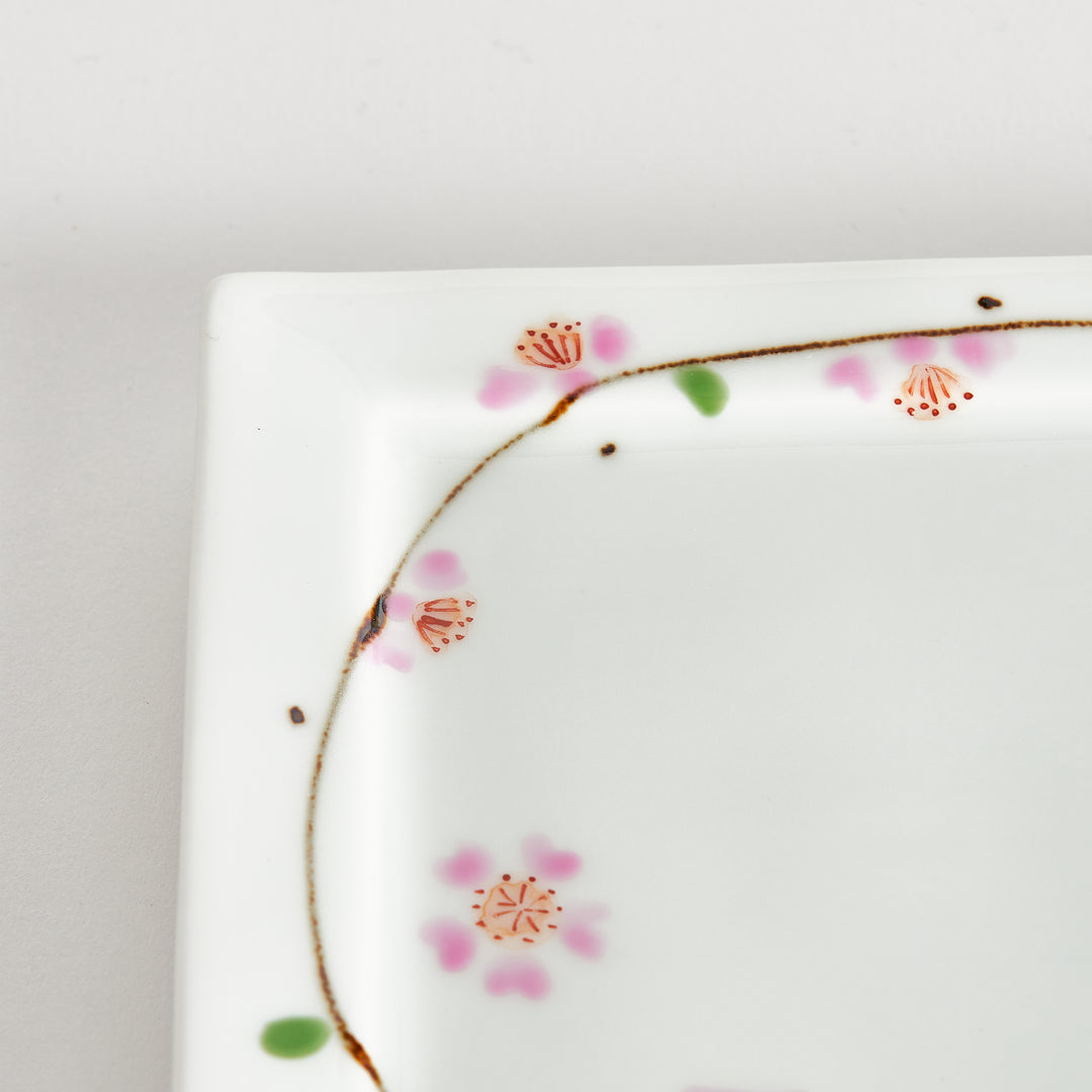 Close-up of the cherry blossom pattern on the dessert plate, focusing on the soft pink petals and green leaves.