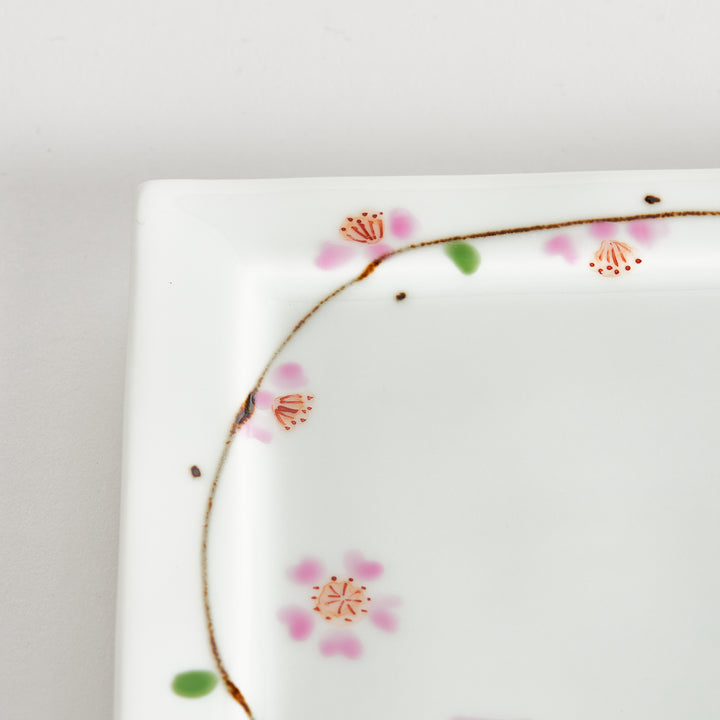 Close-up of the cherry blossom pattern on the dessert plate, focusing on the soft pink petals and green leaves.