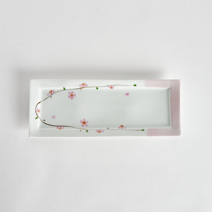 Rectangular serving plate viewed from above, featuring a delicate cherry blossom pattern along one edge with soft pink accents on the corners.