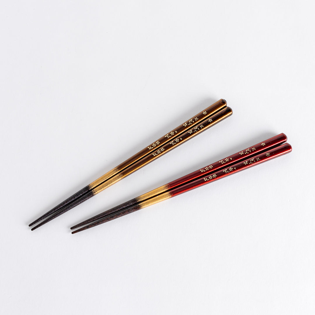 Elegant red and brown lacquered chopsticks adorned with delicate gold cherry blossom motifs, featuring a gradient of gold for added sophistication.