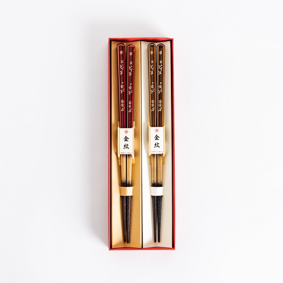 Elegant red and brown lacquered chopsticks adorned with delicate gold cherry blossom motifs, featuring a gradient of gold for added sophistication.