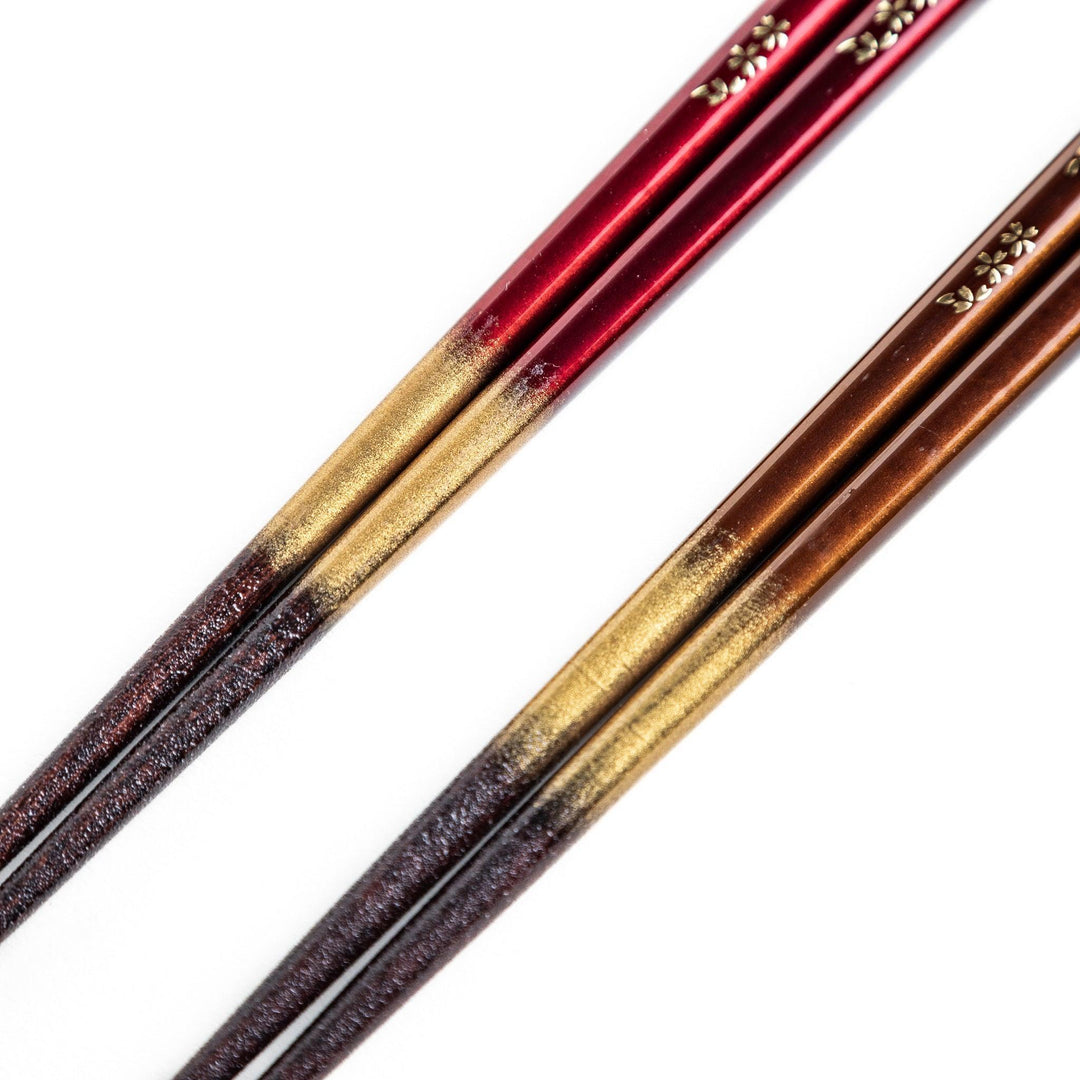 Elegant red and brown lacquered chopsticks adorned with delicate gold cherry blossom motifs, featuring a gradient of gold for added sophistication.