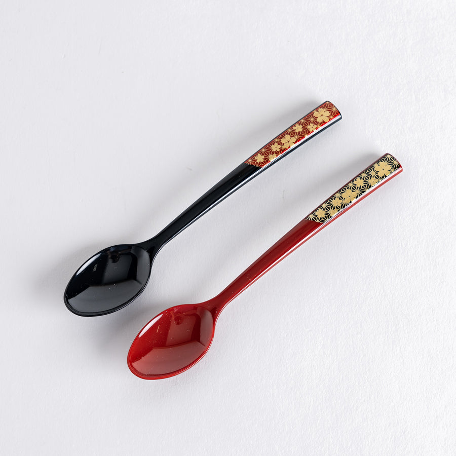 A set of two coffee spoons, one red and one black, featuring a detailed sakura pattern in gold on the handles.