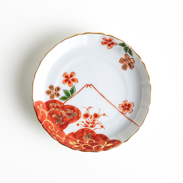 A white ceramic plate adorned with a red floral design and an outline of Mount Fuji in the background.