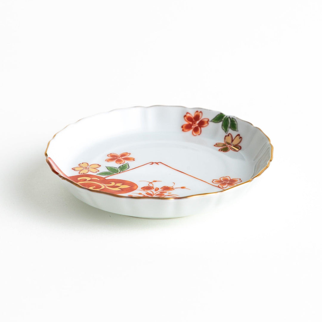 A white ceramic plate adorned with a red floral design and an outline of Mount Fuji in the background.