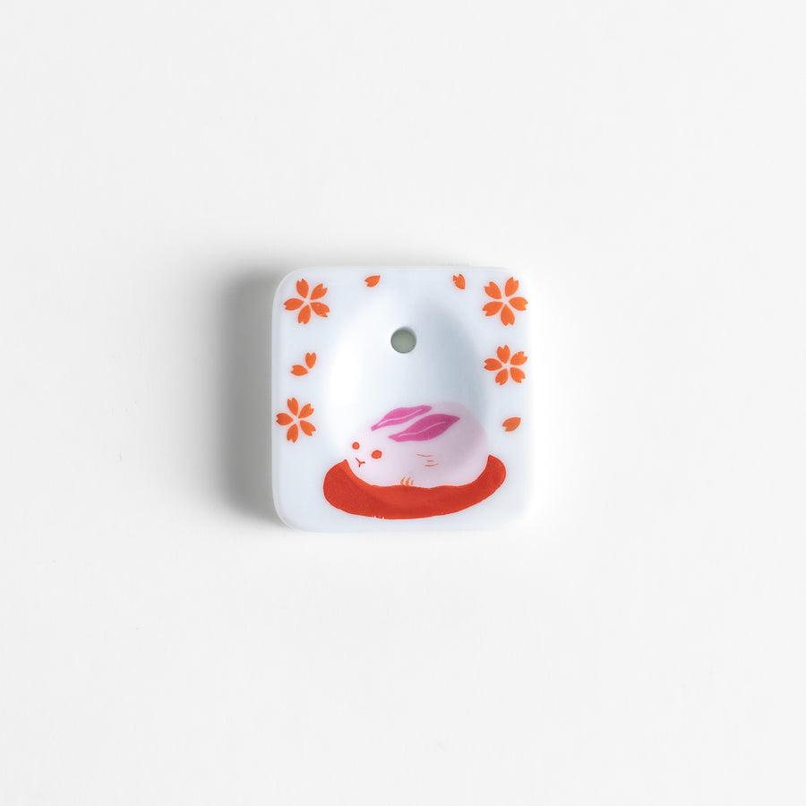 Square ceramic incense holder featuring a delicate sakura rabbit design with pink and red accents, crafted to securely hold incense while adding a charming aesthetic.