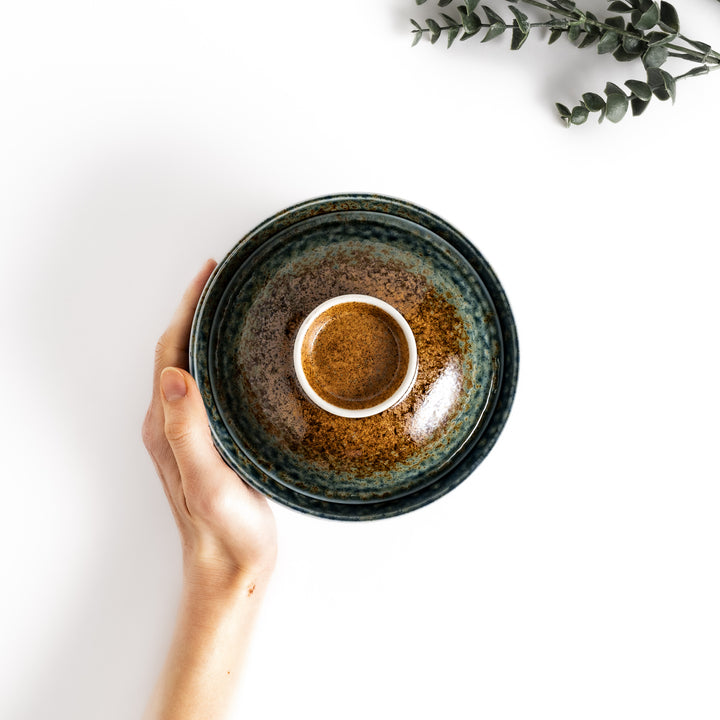 Hand holding a ceramic donburi bowl and lid with a reactive glaze in shades of blue and brown, perfect for serving and enjoying a variety of Japanese dishes.