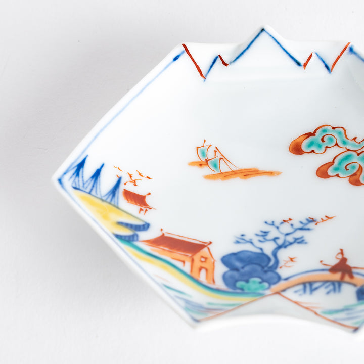 Close-up of a decorative sauce dish, focusing on the vibrant colors and intricate details of the landscape design.