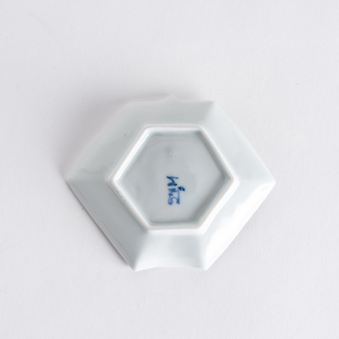 Bottom view of a decorative sauce dish featuring a small maker's mark on its smooth white surface.